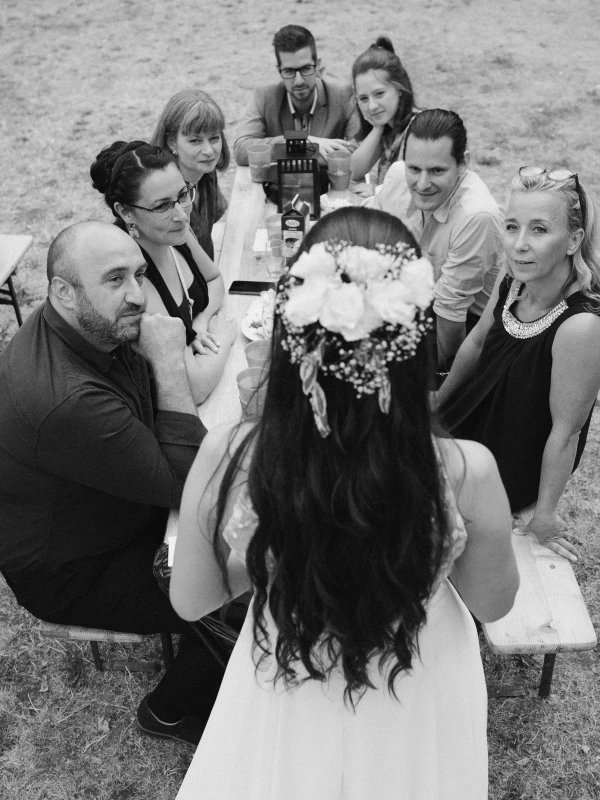 Black and white wedding portrait of bride surrounded by smiling wedding guests.