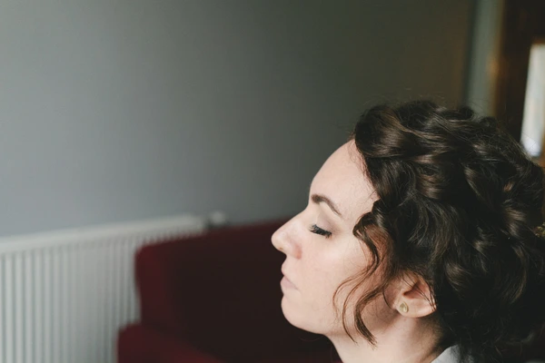 Bride in profile with an ornate updo and closed eyes in soft natural light