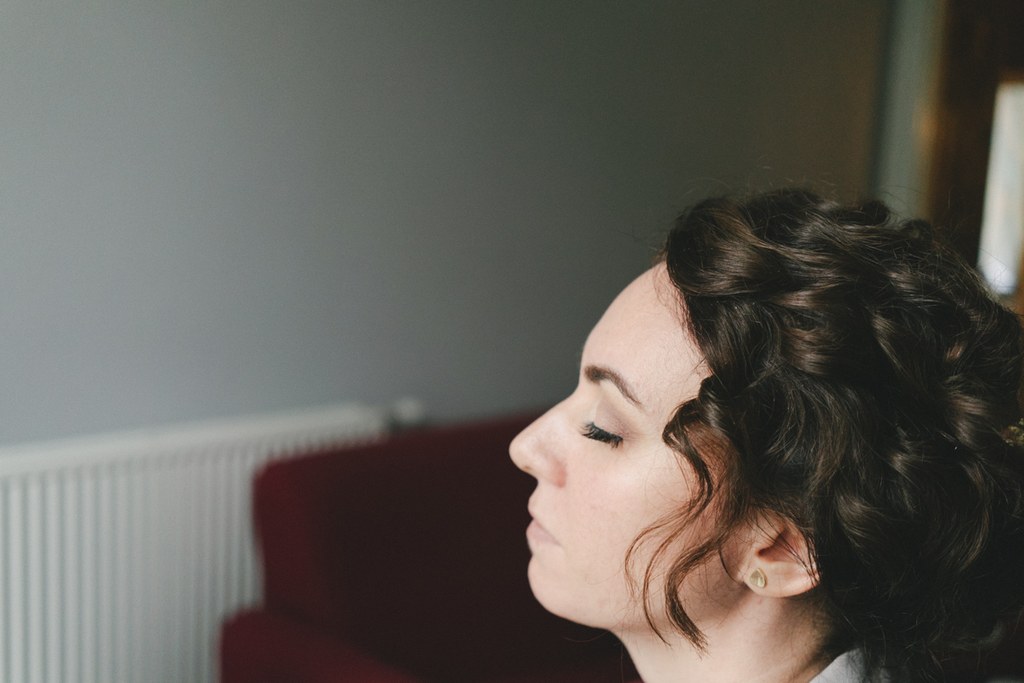 Bride in profile with an ornate updo and closed eyes in soft natural light