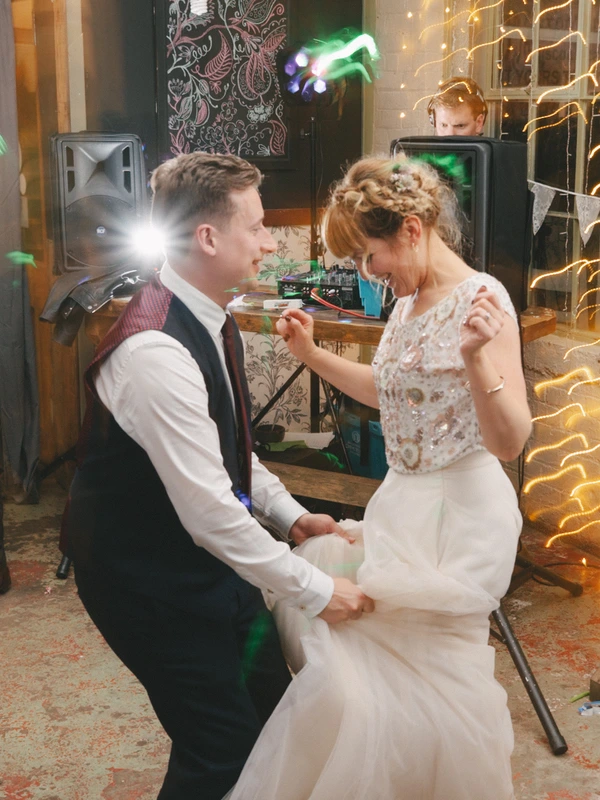 Bride and groom dance in the disco amid colourful LED lights, happily looking at each other