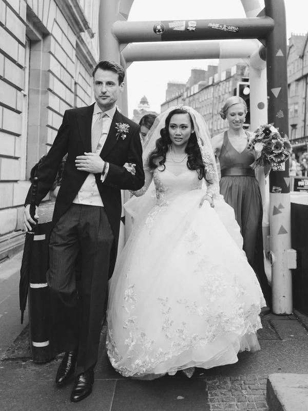Bride and groom in procession through the city — white lace and veil, baroque buildings around