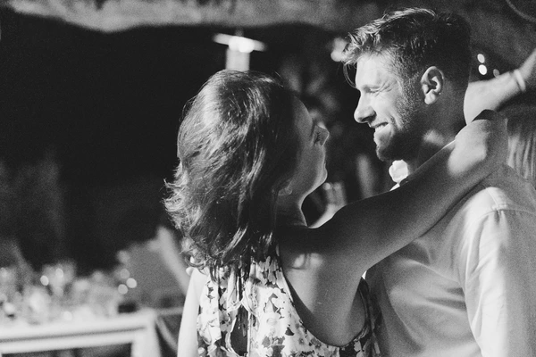 Groom looks lovingly at the bride during the wedding dance — black-and-white, ornate decor behind