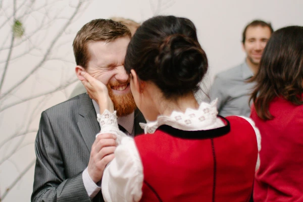 A couple dances together at the wedding reception, the woman laughing with closed eyes and leaning into her partner. Candid documentary wedding photograph.