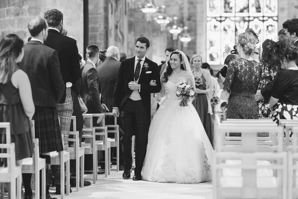 Bride and groom walk smiling towards the altar in the church — guests around, elegant interior
