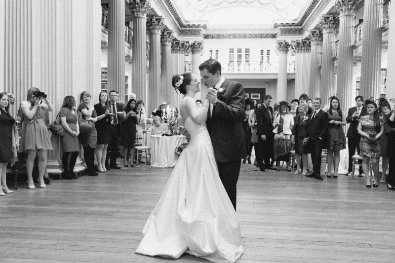 A young wedding couple dancing at their wedding reception surrounded by guests