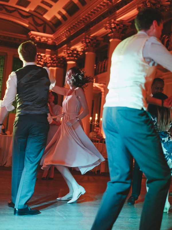 Bride in white dances with the groom at the centre, red and blue stage lighting, elegant hall