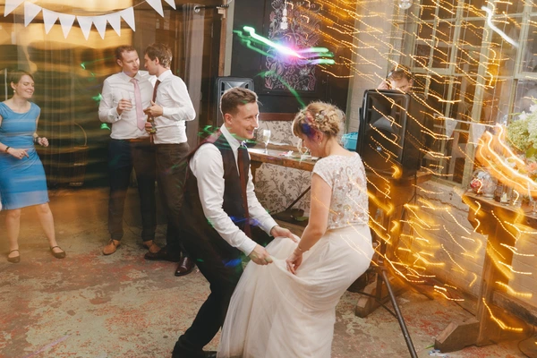 Newlyweds dance joyfully in the decorated wedding salon amid golden light decorations