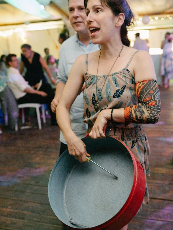Woman dancing with enthusiasm at wedding reception — patterned dress, joyful expression, tent venue celebration.