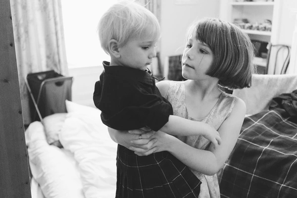 Woman holds a little boy in her arms in a bright room — intimate black-and-white family moment