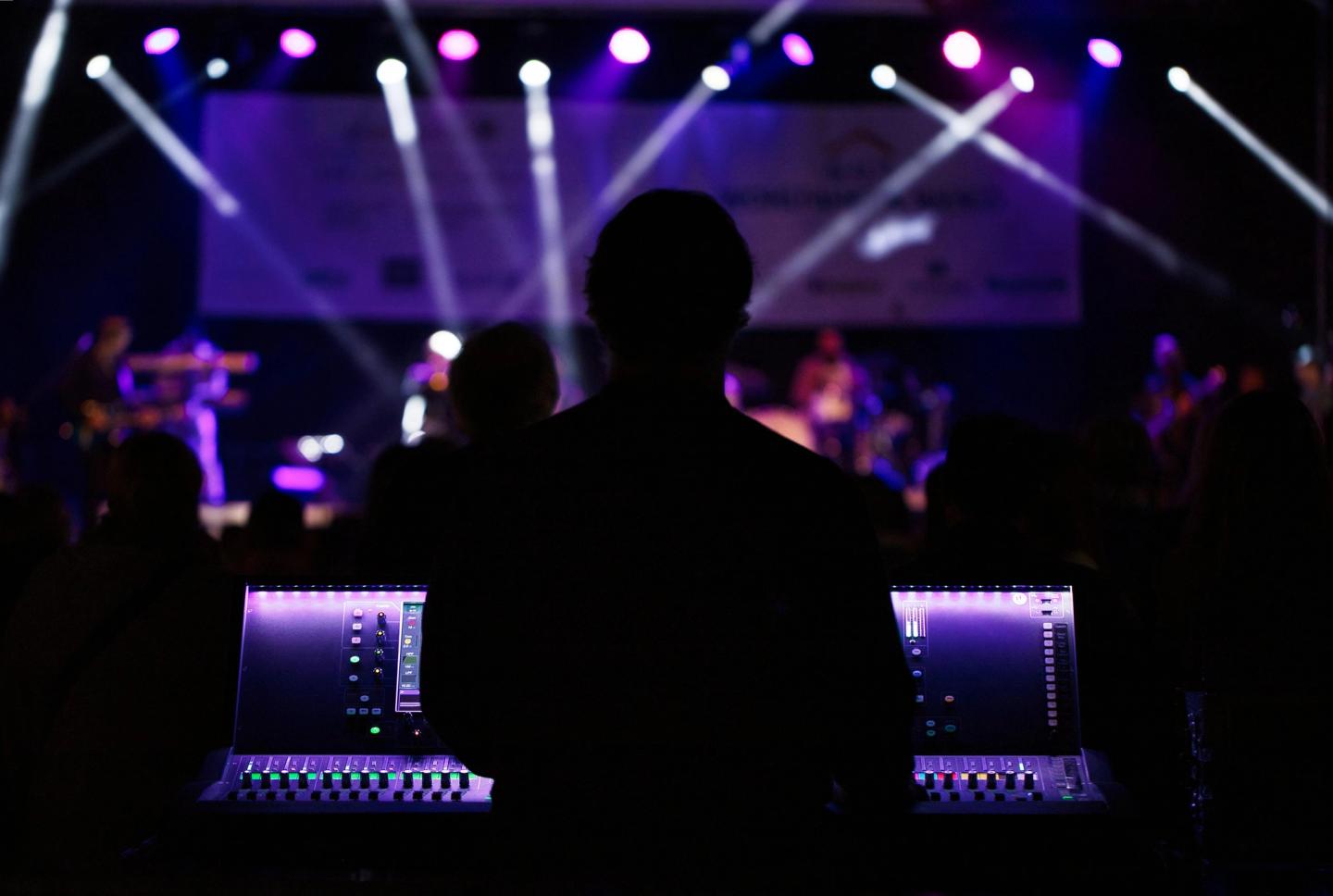 An audio technician manages a soundboard at a live event. Event lighting and audio production by All Stage Productions.