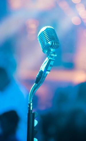 A vintage microphone on a stage with a colorful lighting backdrop.