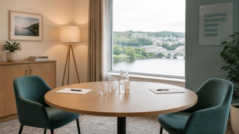 A neutral meeting room with a round table, two chairs and a jug of water
