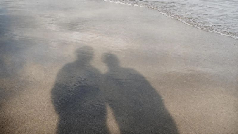 Two overlapping shadows on a quiet Irish beach, symbolising how loneliness and depression can feel similar