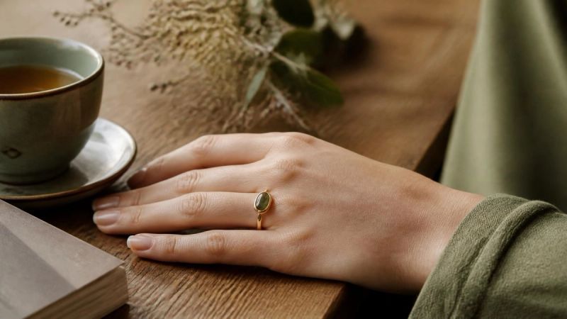 A hand resting on a wooden table near a cup of tea, representing pausing before reacting to irritability
