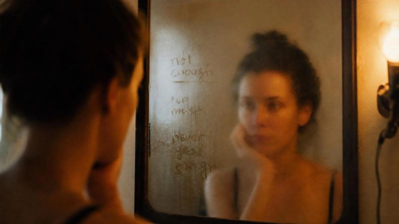 A mirror reflecting a thoughtful face, symbolising the harsh self-criticism that accompanies perfectionism