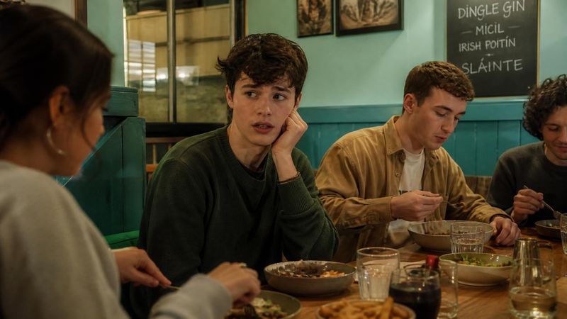 A young person looking anxious while eating with friends at a restaurant