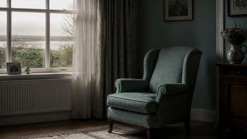 An empty chair beside a window in a quiet room, suggesting loss