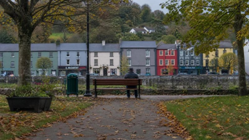 A person sitting alone on a park bench in an Irish town