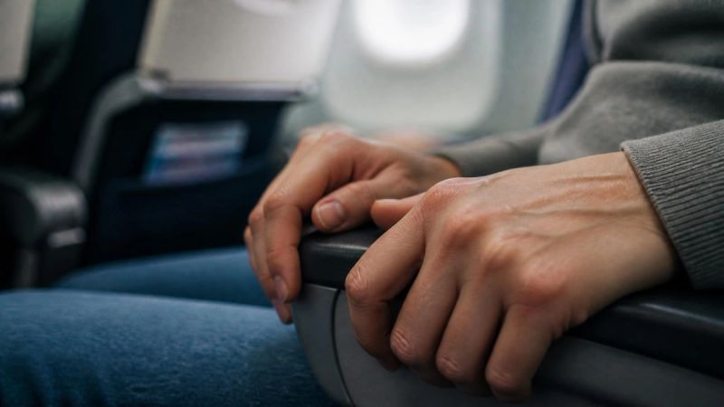 A close-up of hands gripping an armrest, representing the physical symptoms of fear of flying