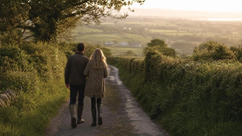 A couple walking together along a green Irish country lane, representing hope and shared support
