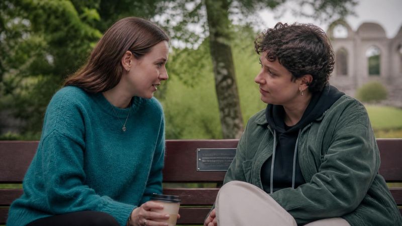 Two women having a quiet supportive conversation on a park bench