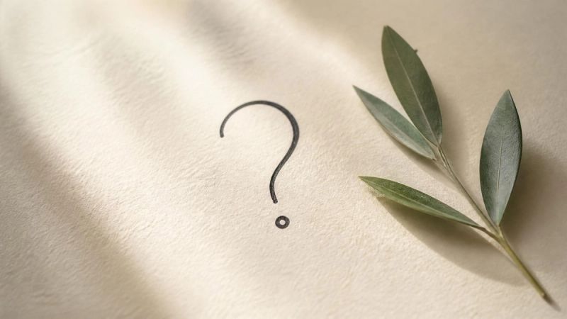 A handwritten question mark on cream paper with a small green leaf