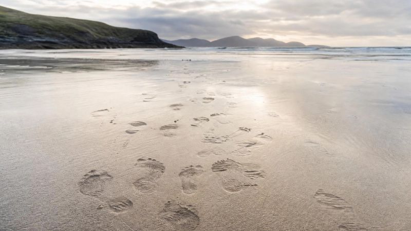 A repeated pattern of footsteps on wet sand, representing recurring emotional patterns after a breakup