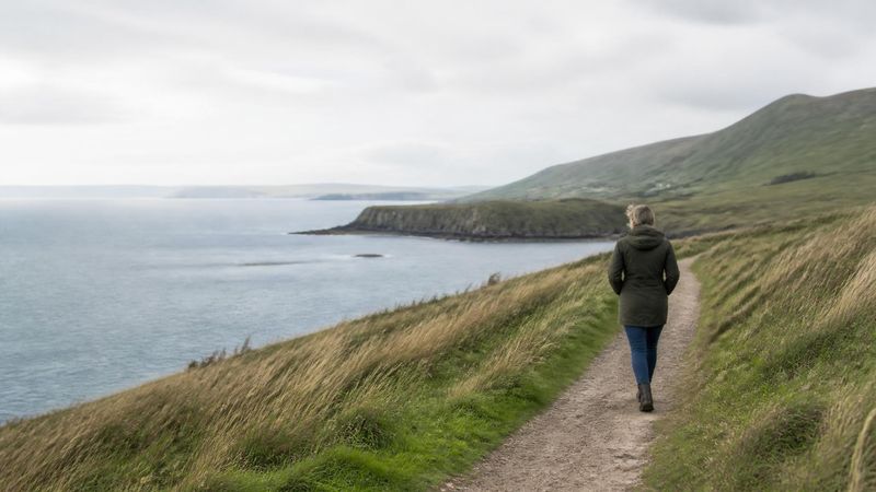 A person walking on a coastal path in Ireland in soft daylight