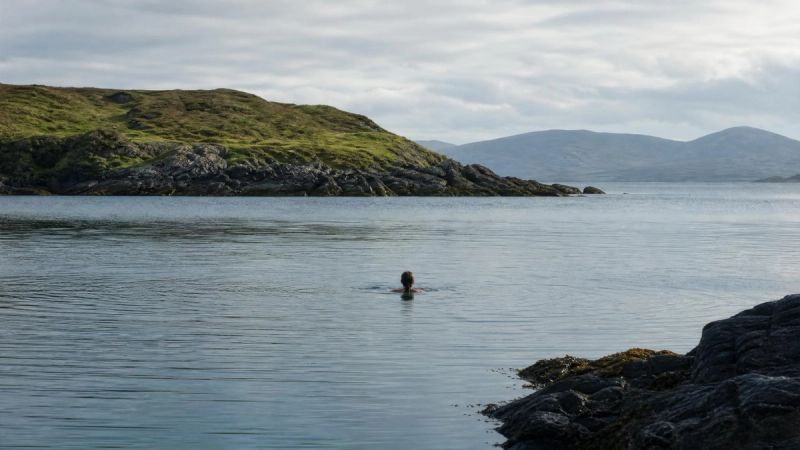 Peaceful swimming scene in a quiet Irish coastal cove, representing moving for enjoyment and being present in the body