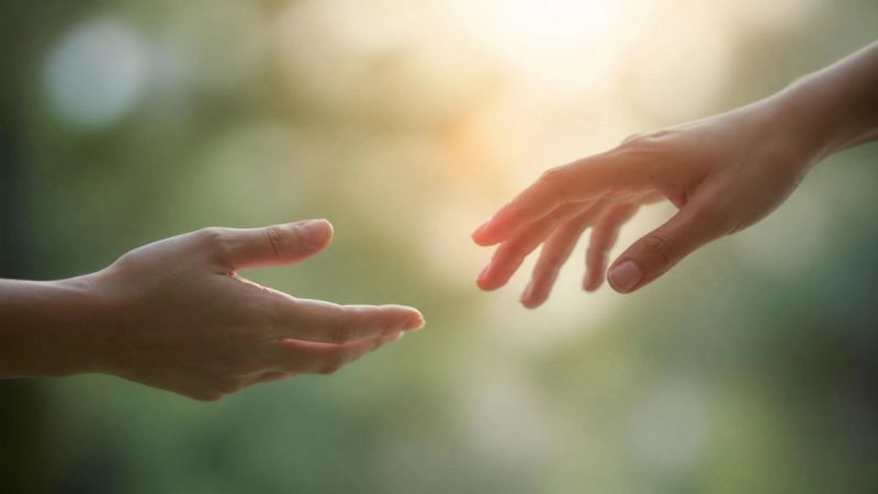 Two hands reaching toward each other across a soft blurred background, representing relationship uncertainty