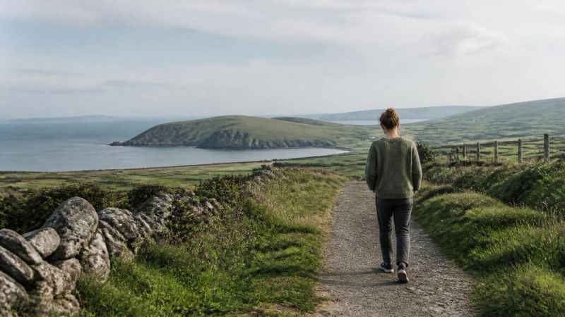 A person walking outdoors on a quiet path, taking a steadying breath