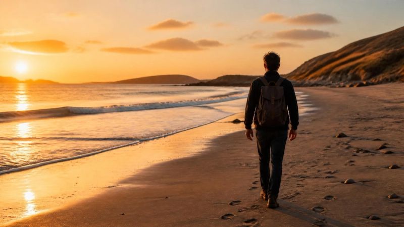 A person walking along a beach in Ireland at golden hour, looking ahead