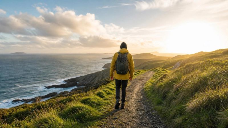 A single person walking towards a brighter horizon on an Irish coastal path