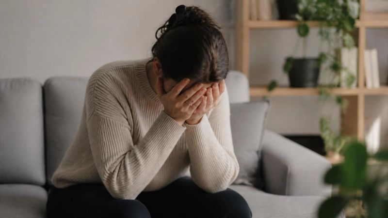 A person holding their head in their hands, representing the link between insomnia and anxiety or depression