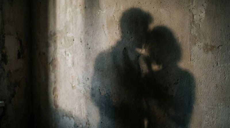Overlapping shadows of two figures on a wall, symbolising how trauma shows up in relationships