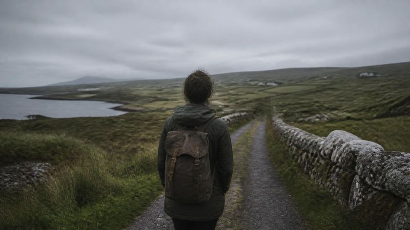 A single person standing on a quiet path, representing individual vulnerability to anger