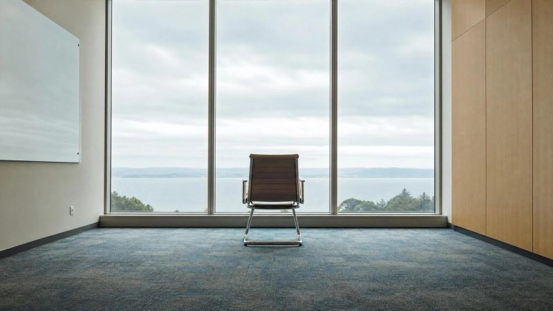A single chair facing a window in an empty meeting room, symbolising feeling alone even when surrounded by people