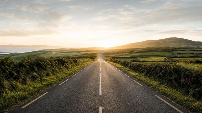 An open country road leading toward a bright horizon, representing taking the next small step to feel less lonely