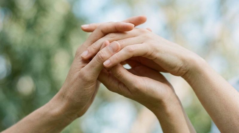 A close-up of intertwined hands, representing the connection between hormones and mental health