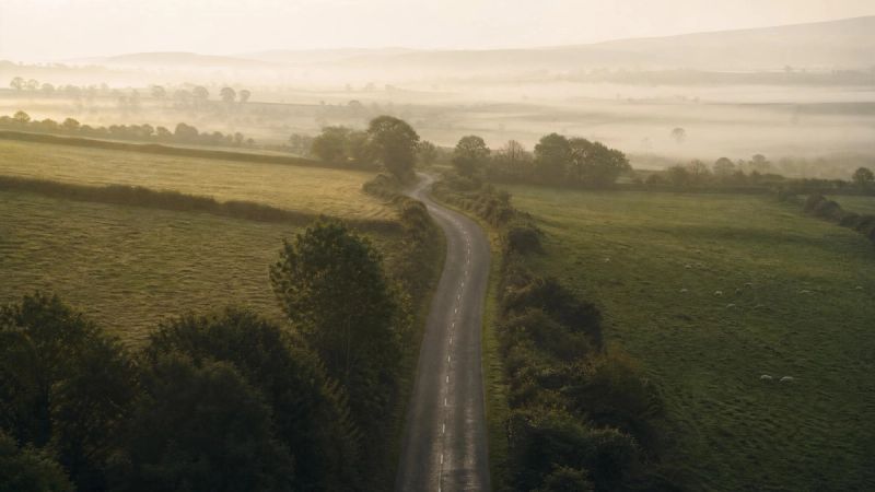 A winding Irish country road through green morning mist, symbolising the journey back to early experiences that shape self-esteem