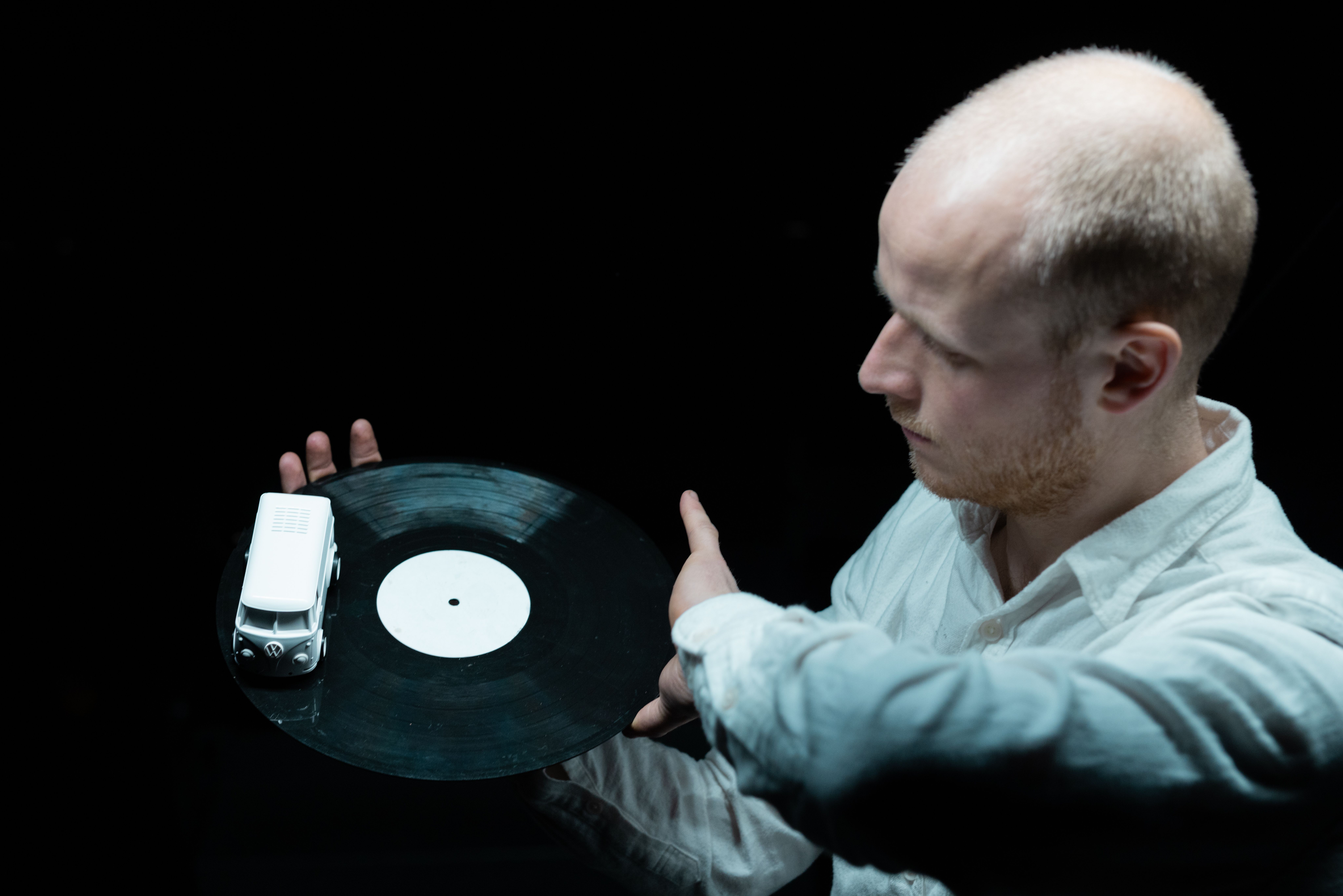 Künstler zeigt eine Schallplatte mit einem Spielzeugauto darauf