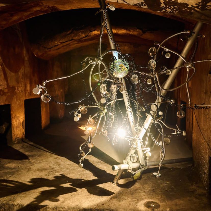 Installation aus Kabeln und Metallstangen, die in einem Gewölbekeller von der Decke hängt