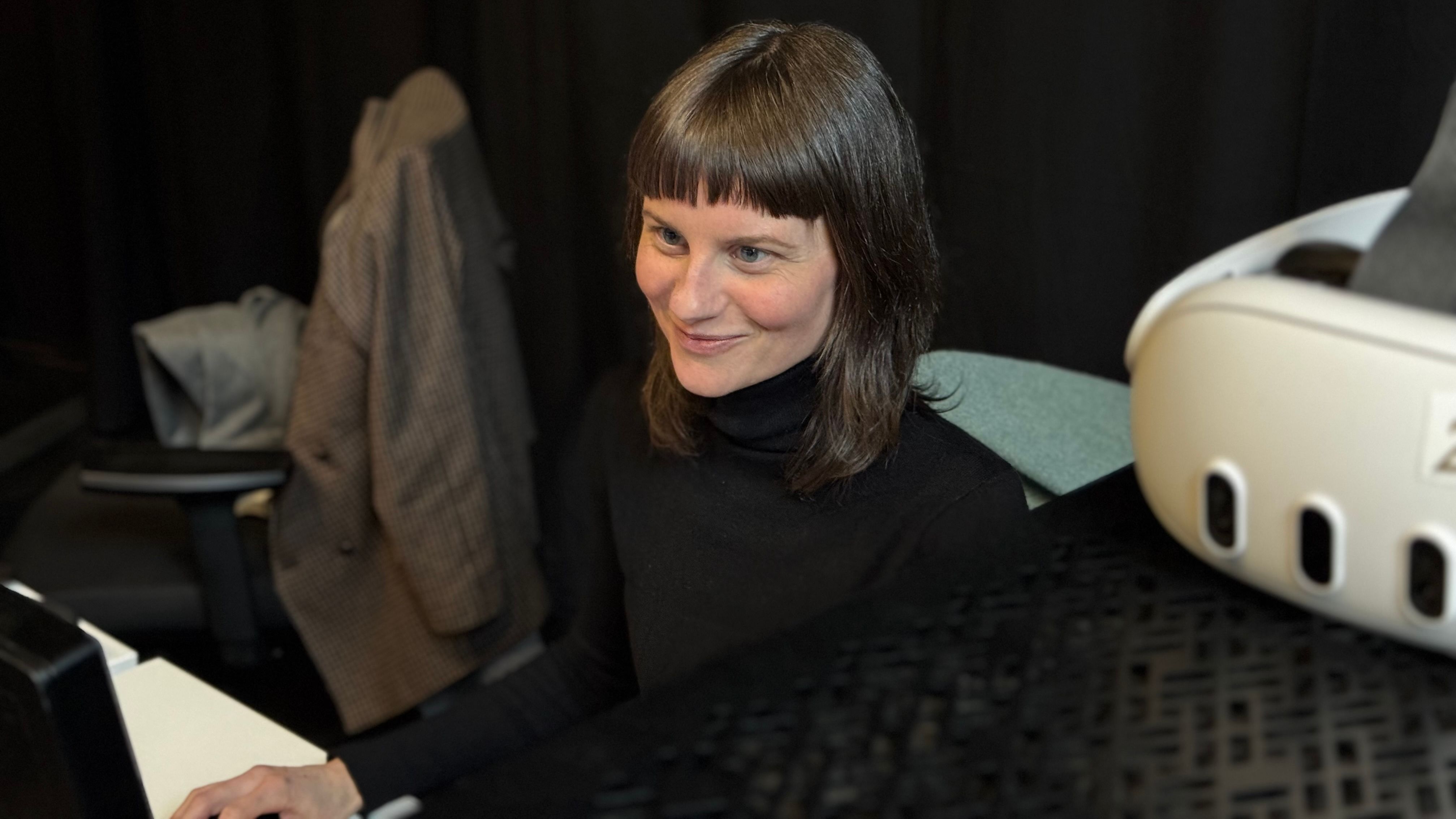 Eine Person sitzt an einem Schreibtisch vor einem Computer