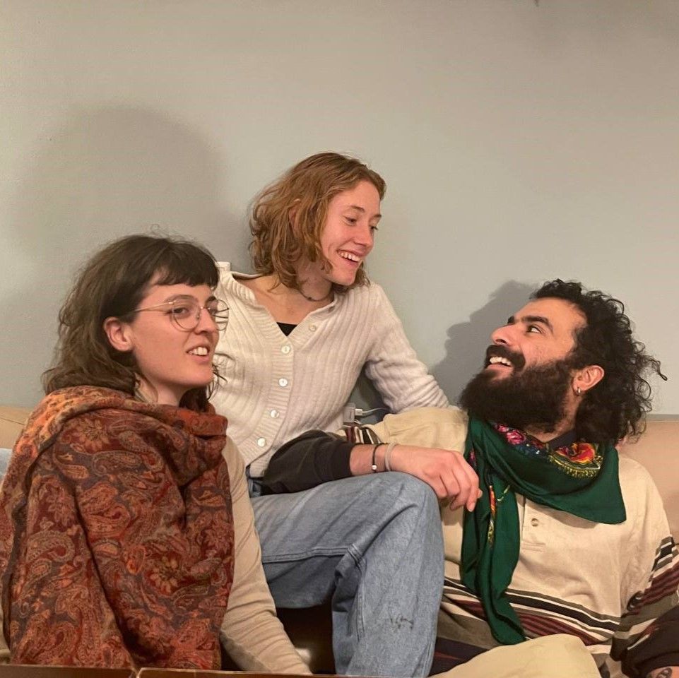 Gruppenbild des Projektteams: Drei Personen sitzen auf einer Couch, zwei schauen sich an, eine Person sieht woanders hin.