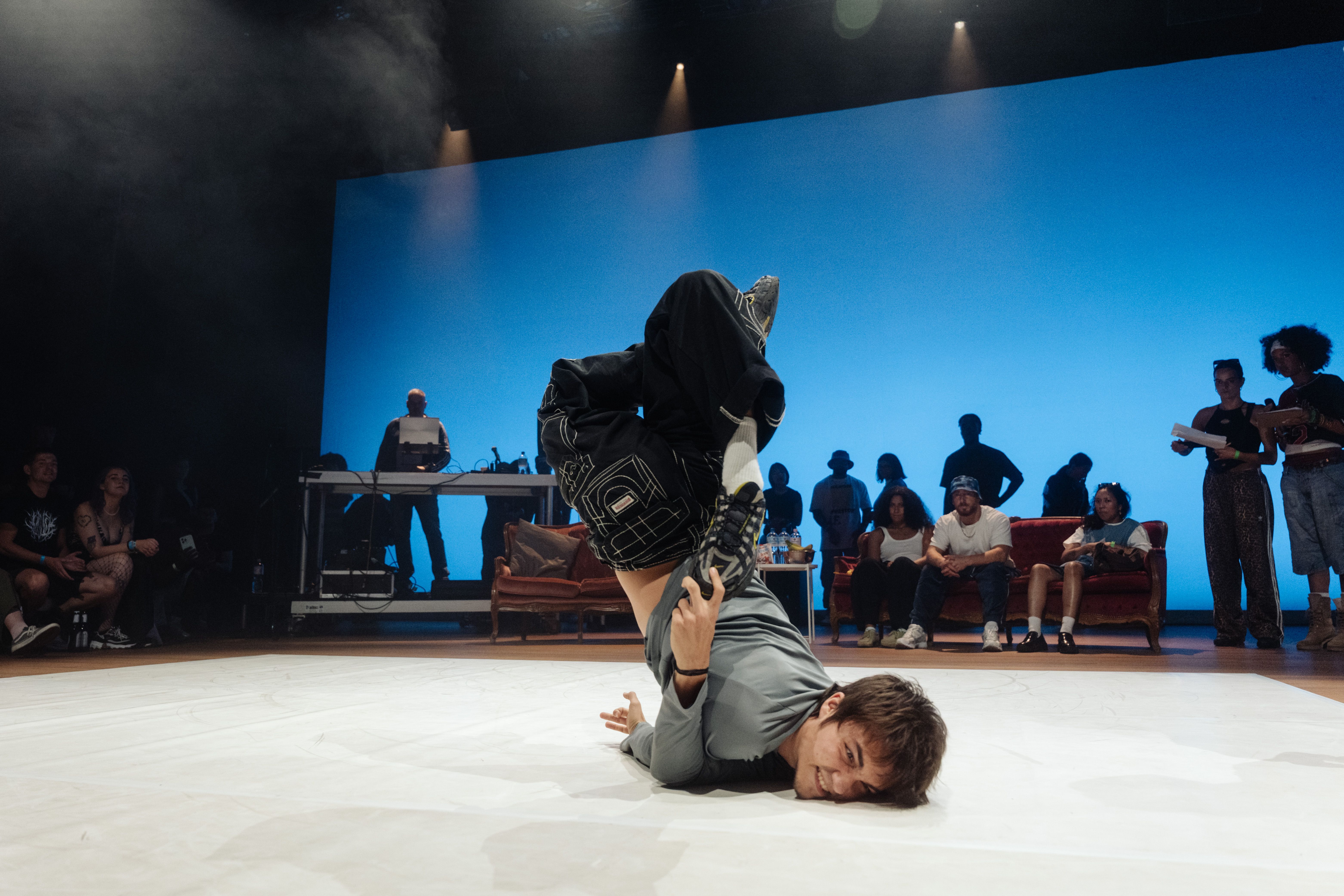 Tänzer, der eine Tanzfigur auf dem Boden macht, Personen sitzen drum herum