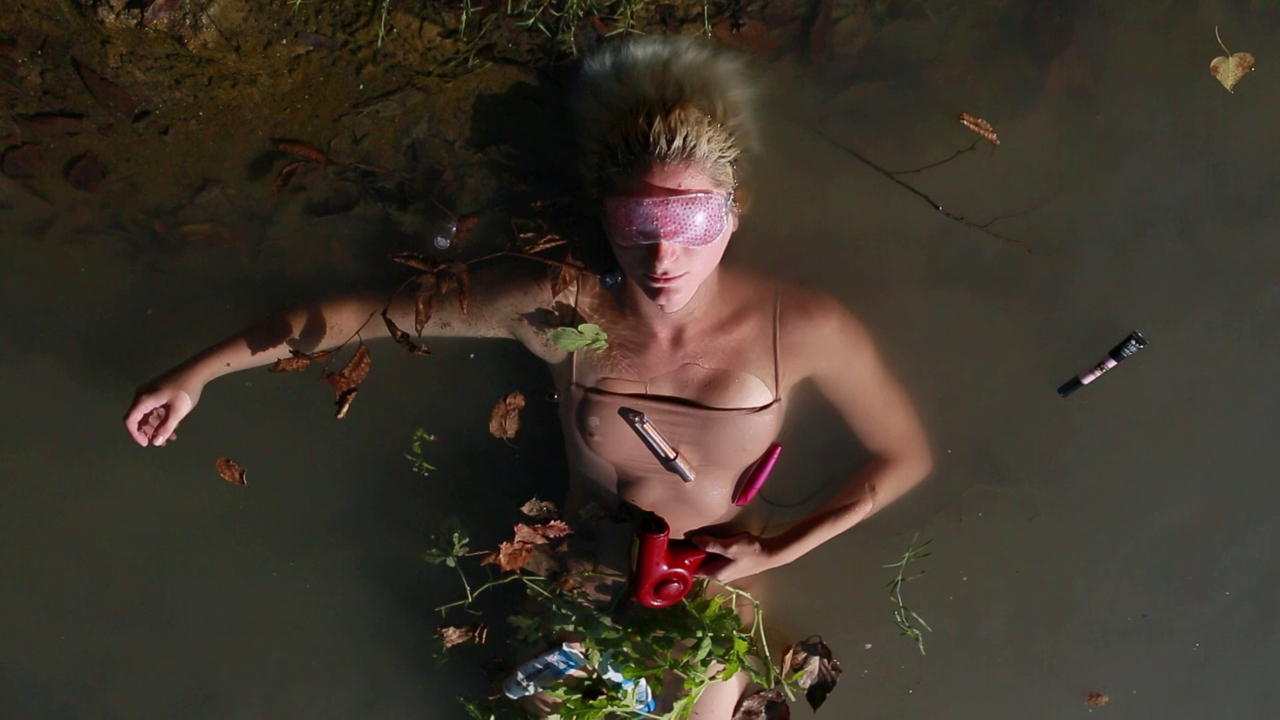 Person liegt im Wasser umgeben von Blättern und Beautyprodukten