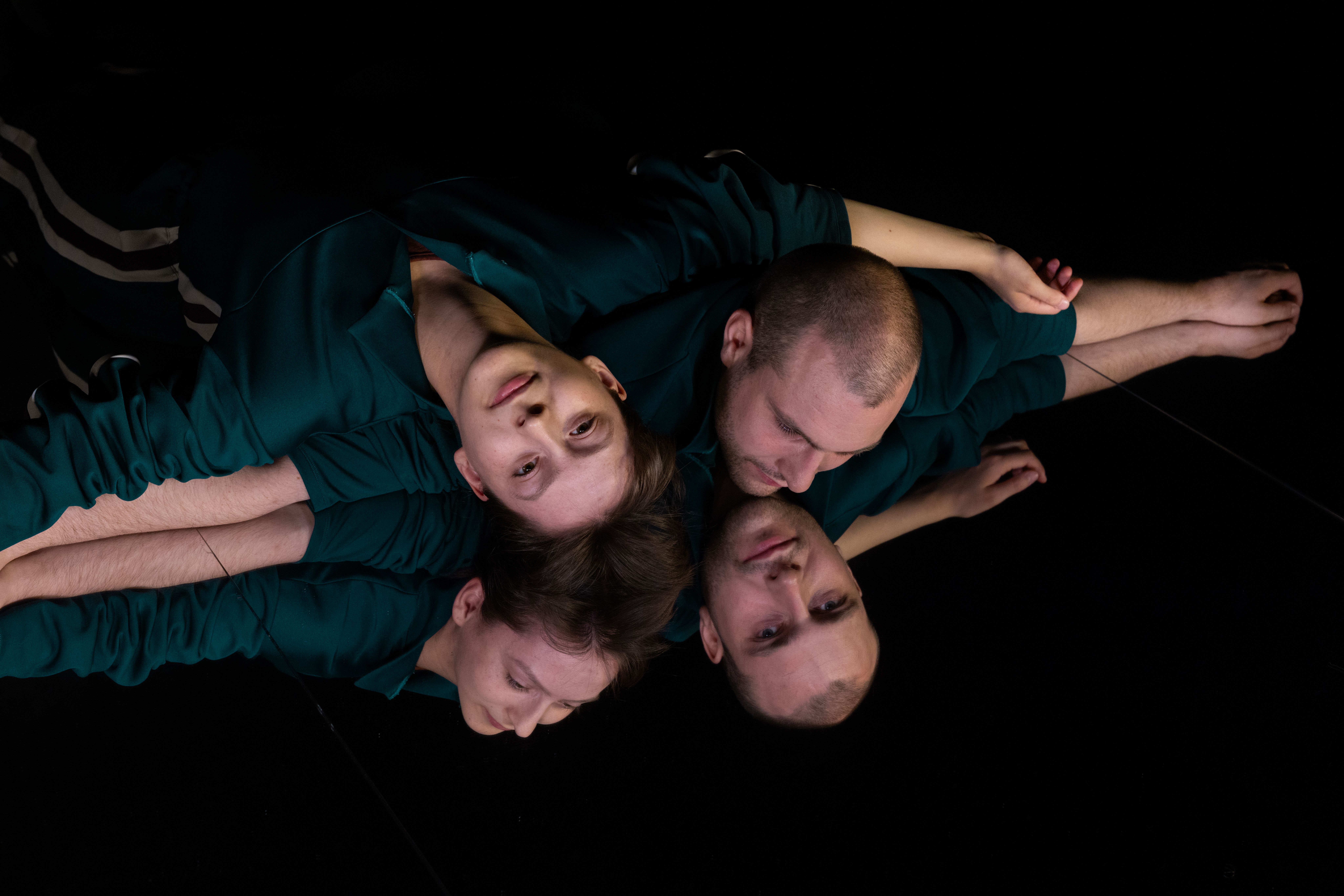Zu sehen sind vier Akrobat*innen, die ihre Köpfe beieinander haben