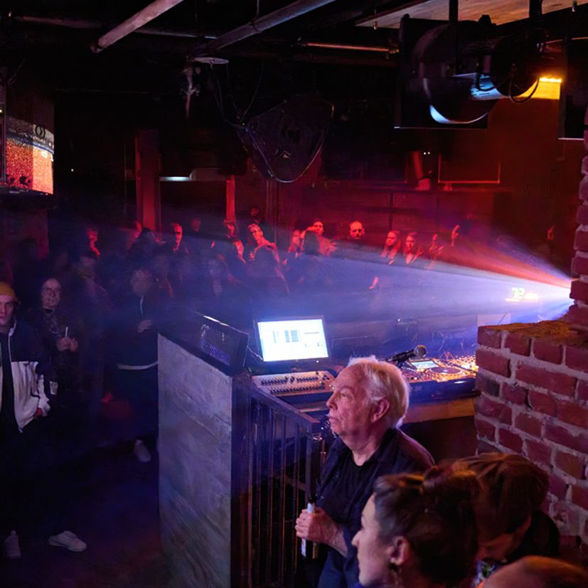 Bild zeigt Club, in dem Menschen stehen und eine Projektion ansehen