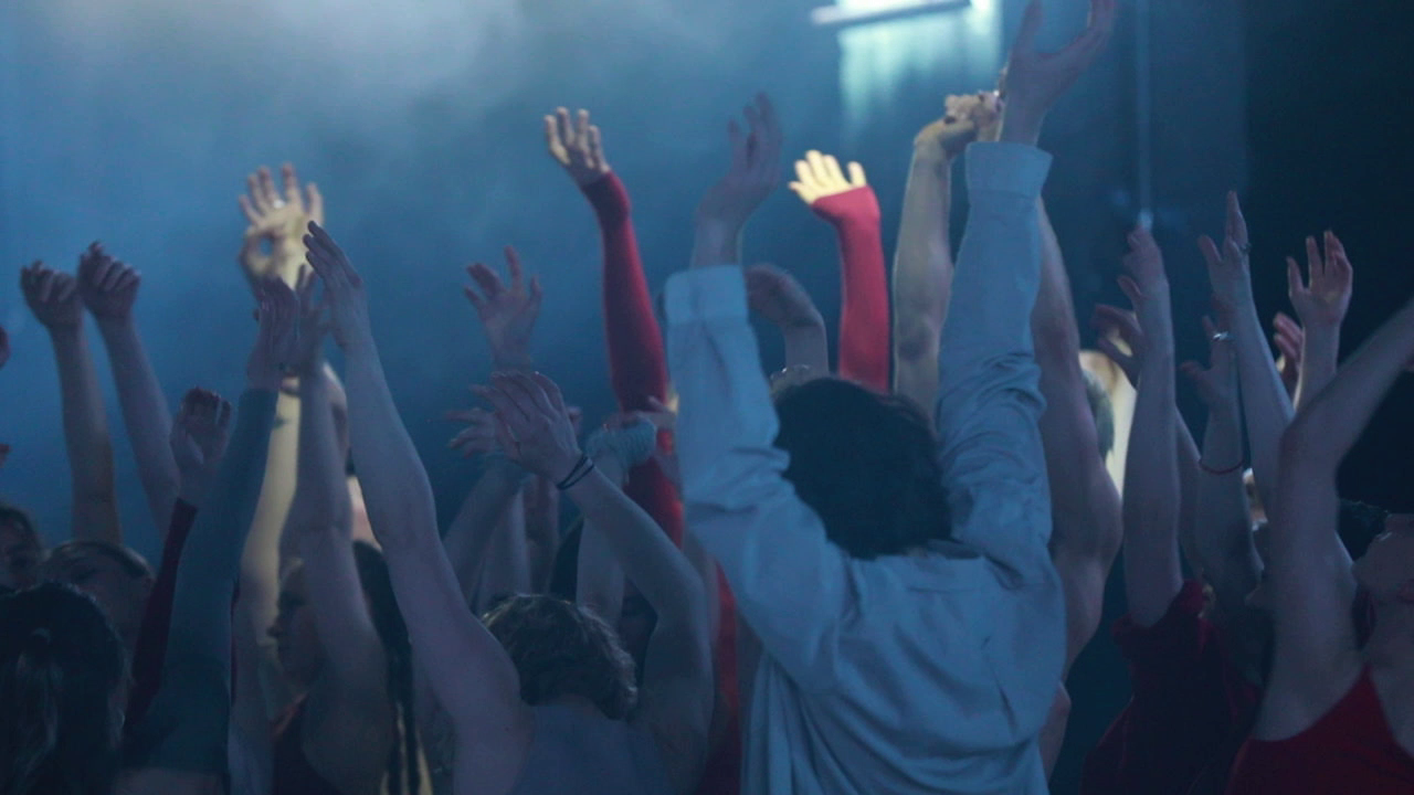 Menschen, die in einem Club tanzen und ihre Hände in die Luft werfen