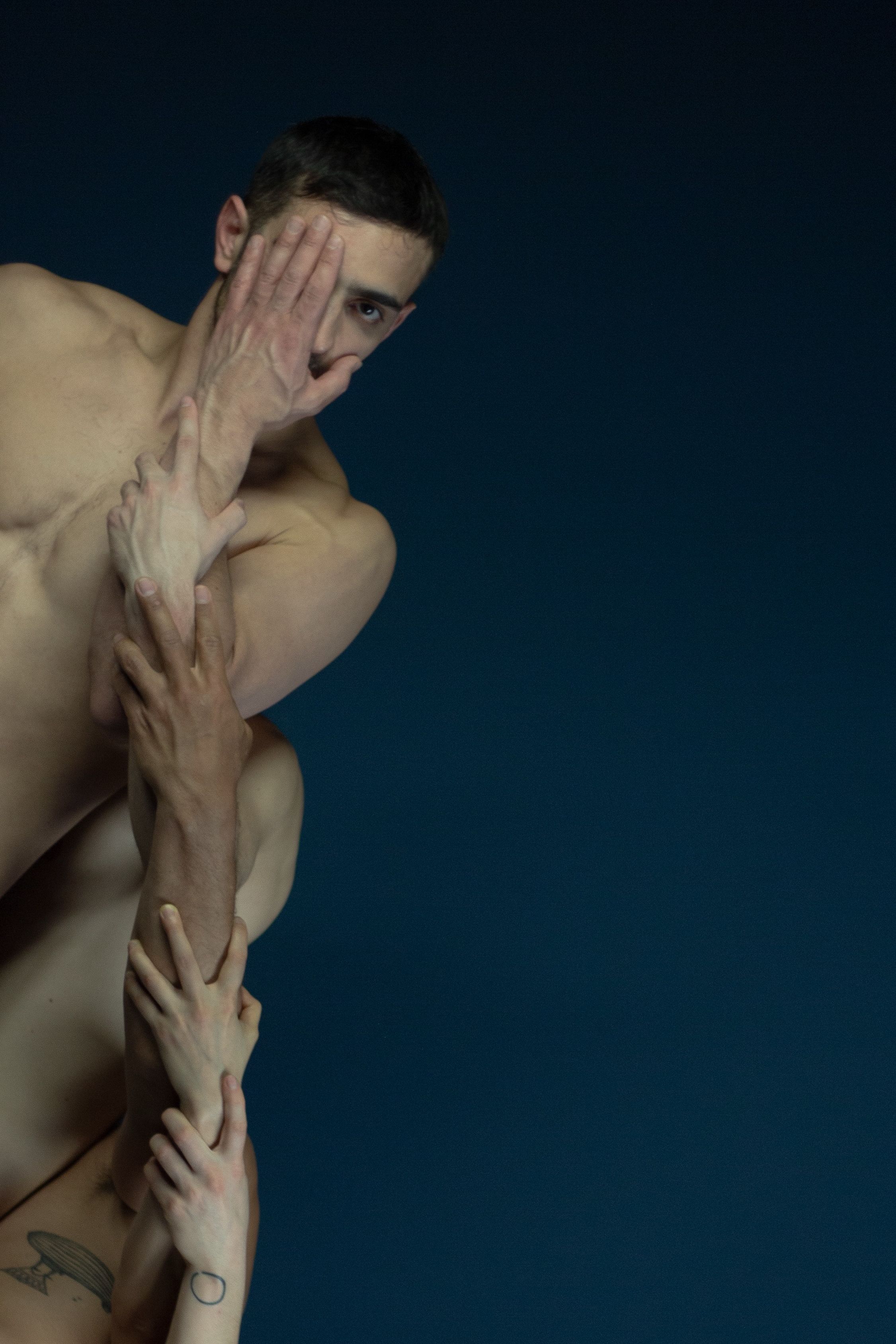 An artist and additional hands or arms in front of a dark background